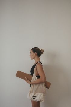 a woman is carrying a large piece of paper in her hand while standing against a white wall