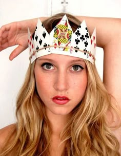 a woman wearing a white crown with playing cards on it's head and blue eyes