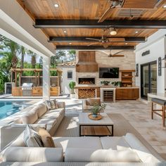 an outdoor living area with couches and tables next to a swimming pool in the background