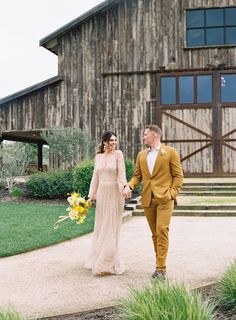 a bride and groom walking down the path to their wedding reception at an old barn