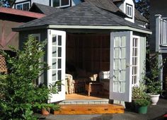 a small white shed sitting in the middle of a yard