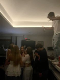 a man standing on top of a counter next to a group of people in a room