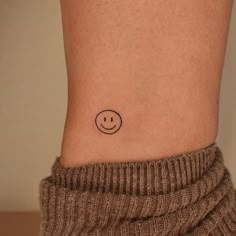 a small smiley face tattoo on the side of a woman's right leg,