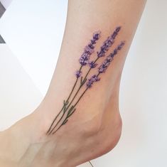 a woman's foot with lavender flowers tattooed on the bottom of her leg,