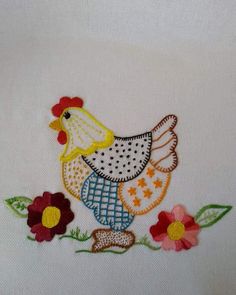 a white shirt with a chicken and flowers on it's left side, embroidered onto the chest