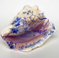 a blue and white shell shaped object on a white surface with flowers in the center