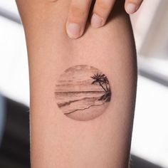 a woman's arm with a small palm tree tattoo on the left side of her calf