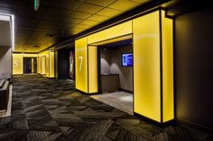 an empty hallway with yellow walls and black carpeting, in the middle of a building