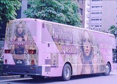 a pink bus is parked on the side of the road in front of tall buildings