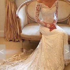 a woman is sitting on a couch wearing a wedding dress with long sleeves and lace