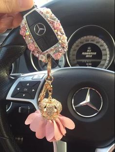 a mercedes keychain with a pink flower attached to it's center console