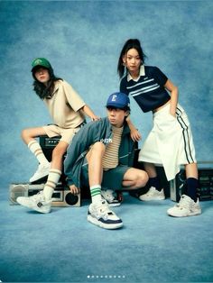 three young people posing for a photo with their suitcases and tennis shoes in front of them