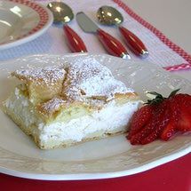 a piece of cake with powdered sugar and strawberries on the plate next to it