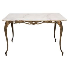 a marble top table with metal legs and an ornate design on the base, against a white background