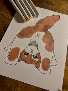 a brown and white dog laying on top of a table next to some crayons