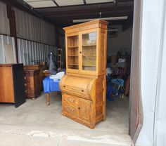 an old wooden desk and hutch in a storage room with blue table cloth on the floor