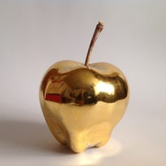 an apple shaped object with a stick sticking out of it's side on a white surface