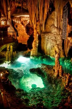 the inside of a cave filled with water and caves are lit up by green lights