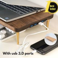 a laptop computer sitting on top of a wooden table next to a charger and power strip