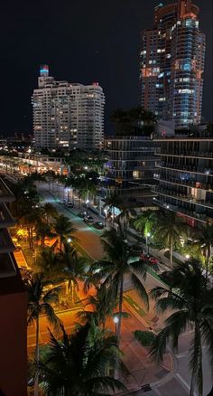 an aerial view of a city at night with palm trees and buildings in the background