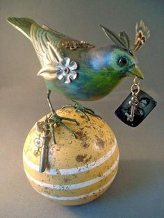 a bird sitting on top of a yellow ball with a key hanging from it's side