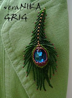 beaded brooch with green leaves and blue stone in the center, on a green shirt