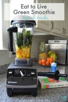 a blender filled with fruit and vegetables sitting on top of a counter next to a book