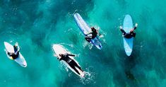 three people on surfboards paddling in the blue ocean water, top view from above