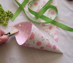 someone is cutting paper with scissors on a table next to some flowers and green ribbon