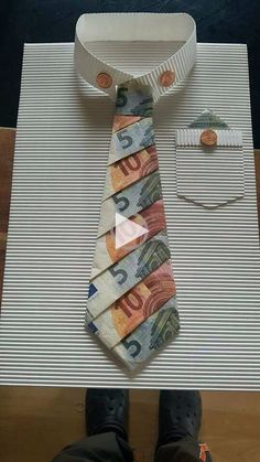 a tie made out of money sitting on top of a table next to a person's feet