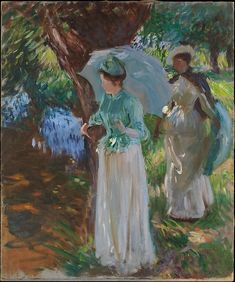 two women standing under an umbrella in the shade by a tree, one woman is wearing a white dress and the other has a green hat