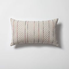 a white pillow with red and green lines on it, against a white wall background