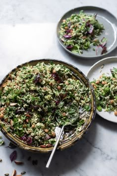 two plates filled with salad on top of a marble countertop next to each other