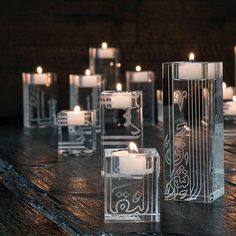 candles are lined up on a table with decorative glass blocks and votives in the background