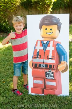 a young boy standing next to a lego poster