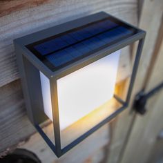 a solar powered light mounted on the side of a wooden wall next to a door