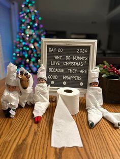 three small figurines dressed in white sitting next to a sign that says, why do mums love christmas? because they are good - wrappers