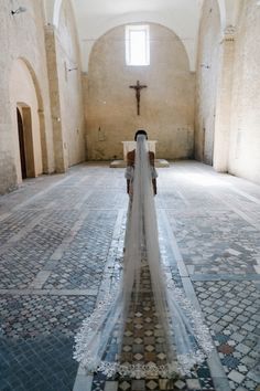 a woman in a wedding dress is standing in the middle of an empty church aisle