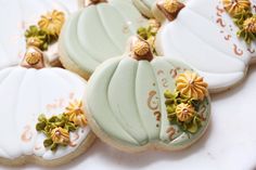 several decorated cookies sitting on top of a white tablecloth with gold trimmings