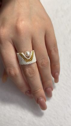 a close up of a person's hand wearing a ring with pearls on it