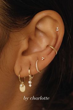 a woman wearing three different types of ear piercings