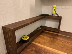 a wooden shelf sitting on top of a hard wood floor next to a white wall