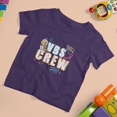 a purple t - shirt with the words wbs crew on it next to toys