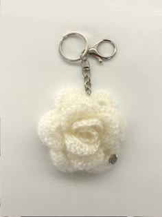 a crocheted key chain with a white flower on it's end and a metal hook in the middle