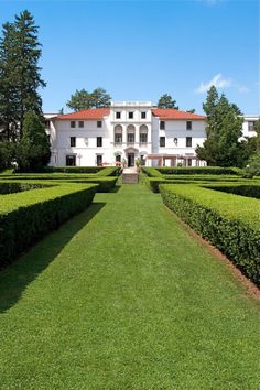 a large white house surrounded by hedges and trees