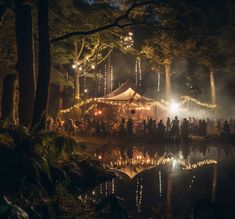 a group of people standing in front of a tent at night with lights on the trees