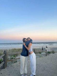 two people hugging each other on the beach