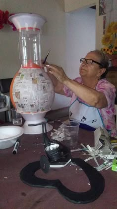 an older woman is making a paper mache