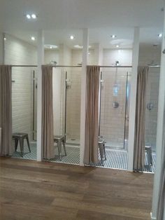 a bathroom with three separate shower stalls and a wooden floor in front of the bathtub