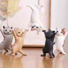 several small plastic cats standing on top of a wooden floor next to a framed photo